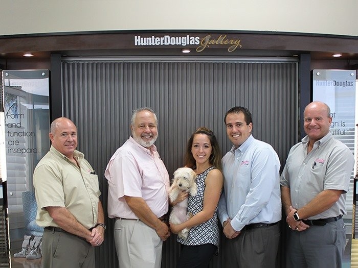 Five employees standing in front of Hunter Douglas Gallery display