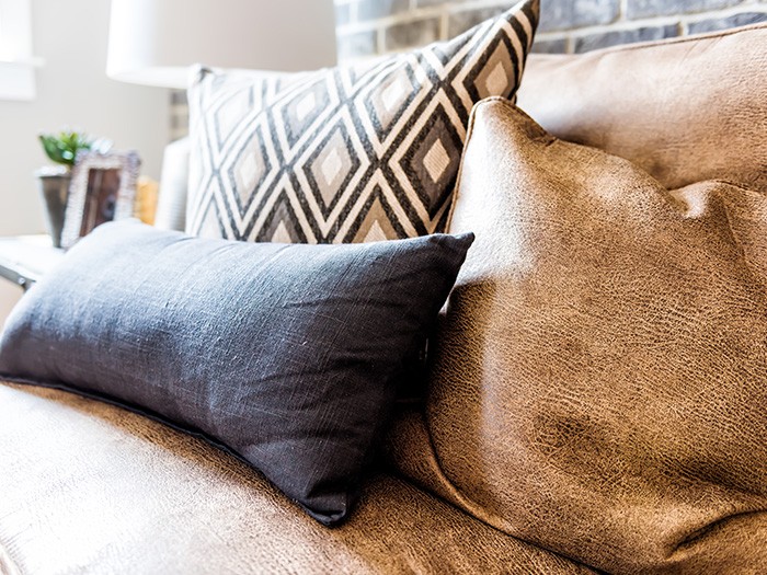Brown leather furniture with blue and pattern throw pillows. 