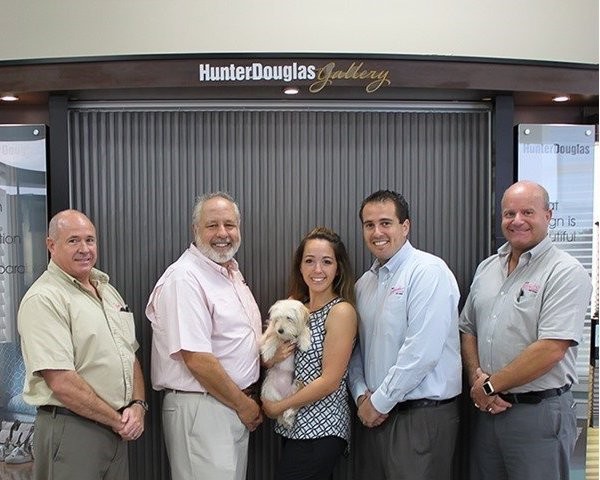 Five employees standing in front of Hunter Douglas Gallery display
